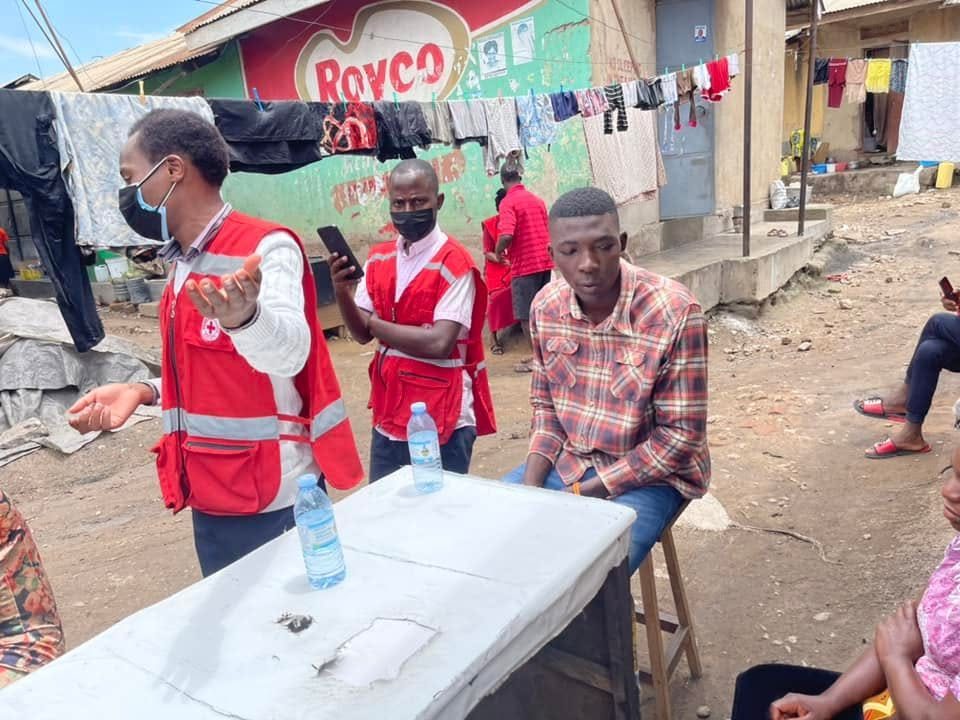 Red Cross volunteers lead a conversation with residents around a table in a busy neighbourhood